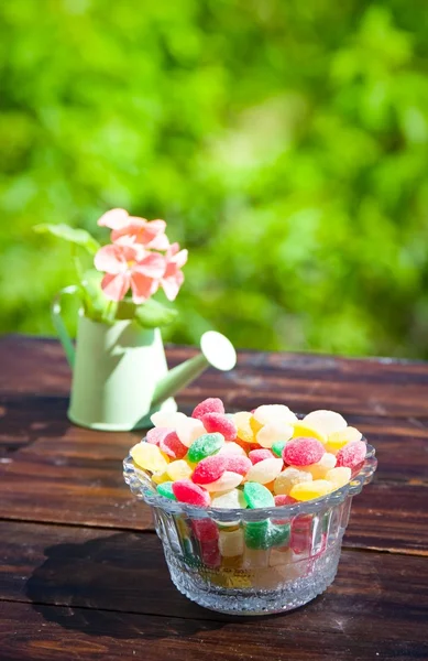 Monpase and flowers in can on table in garden. Focus on candy — Stock Photo, Image