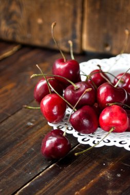 Tahta masadaki kirazlar ve su damlaları.