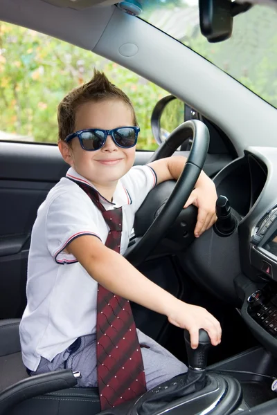 Cute driver in sunglasses and tie sits in car — Stock Photo, Image