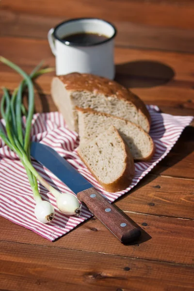 Rye bread, onion, beer and knife on wood, outdoor. Focus on onion — Stock Photo, Image