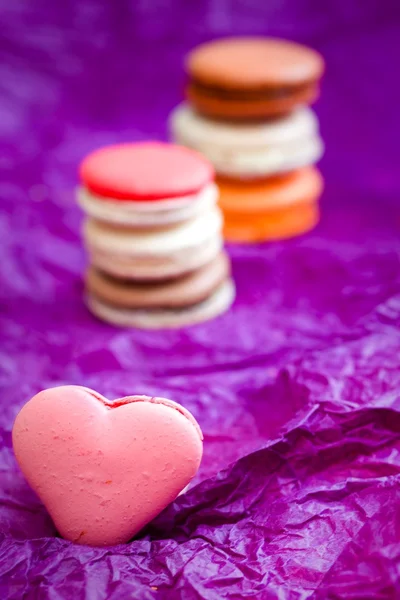 French colorful macarons with hearts on violet background — Stock Photo, Image
