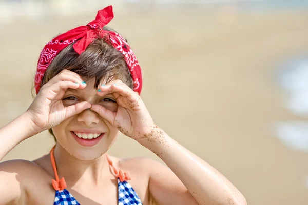 Girl looking through imaginary binocular on beach — Stock Photo, Image