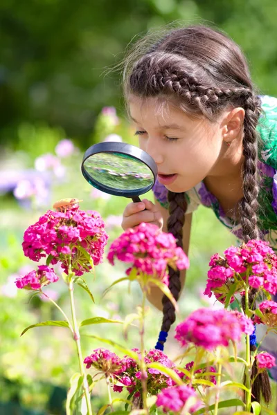 Překvapený dívka dívá skrz zvětšovací sklo na brouka — Stock fotografie