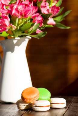 Macaroons ve ahşap arka plan üzerinde pembe çiçekler