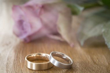 Gül arka planda bir masada iki alyans