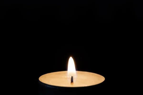 Um tealight ardente na escuridão, close-up — Fotografia de Stock