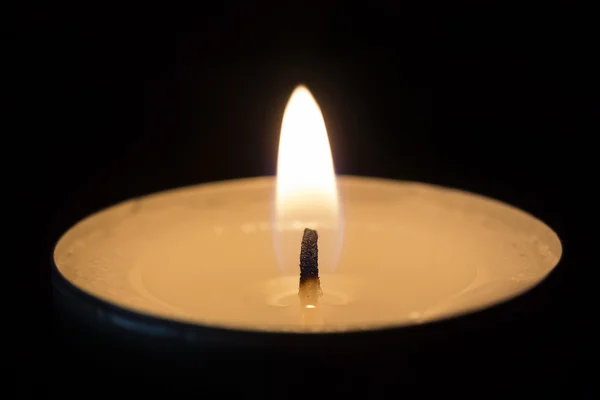 One burning tealight in darkness, closeup Royalty Free Stock Photos