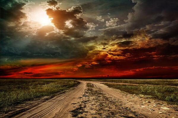 Rural road through the field before the storm