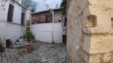 İtalya, Casamassima 'da, ünlü Mavi Apulia Köyü' nde bir ortaçağ geçidinde huzurlu bir yürüyüş. Eski şehrin kalbinde taş duvarlar, kemerler ve tarihi mimari.