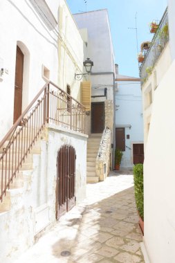 İtalya 'nın mavi kasabası Apulia olarak bilinen Casamassima' nın tarihi merkezinde, beyaz boyalı binaları ve geleneksel taş merdivenleri olan büyüleyici dar bir sokak. Parlak gün ışığı, Akdeniz mimarisi ve barışçıl atmosfer.