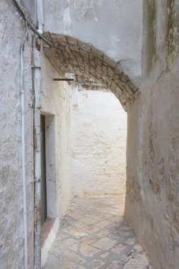 Güney İtalya 'nın karakteristik mavi köyü Casamassima' nın tarihi merkezinde, kırsal kemer yolu ve yumuşak doğal ışığı olan dar bir taş sokak..