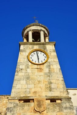 Tarihi taş saat kulesi Casamassima, Mavi Şehir 'de canlı mavi bir gökyüzünün altında duruyor. Mimari detaylar, sıcak ışık ve antik dokular bu ikonik simgenin cazibesini vurgular..