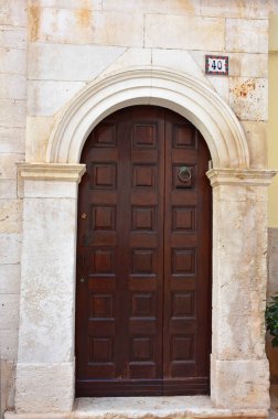 Casamassima 'nın tarihi merkezi Mavi Kasaba' da oyulmuş taş çerçeveli zarif ahşap kapı. Geleneksel Akdeniz mimarisi ve işçiliğinin incelikli bir örneği..