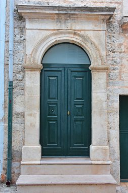 Casamassima 'nın tarihi merkezinde, Mavi Kasaba' da zarif kemerli kapı. Taş perisi ve yeşil ahşap kapı geleneksel güney İtalyan mimarisini ön plana çıkarıyor..