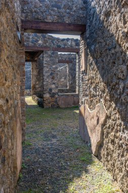 İtalya 'nın güneyindeki Pompeii arkeoloji sahasındaki antik bir Roma evinin iç taştan geçidine bakın. Korunmuş duvarlar ve döşemeler, Antik Roma 'daki iç mimari ve günlük yaşamı gösteriyor..