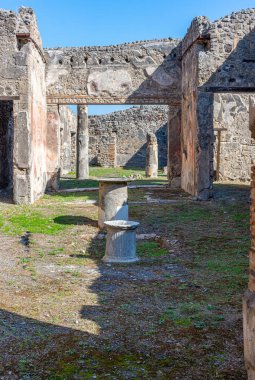 Pompeii, İtalya 'da bulunan antik bir Roma evinin iç avlusunda merkezi bir taş sunak, sütunlar ve etrafındaki harabeler yer alıyor. Antik çağlardan kalma iyi korunmuş yerli mimari.