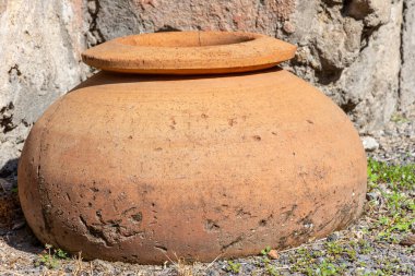 Pompeii, İtalya 'da kısmen toprağa gömülü büyük bir Roma terasotta saklama kavanozunun yakın çekimi. Antik çağlarda yiyecek veya sıvı depolama için kullanılan arkeolojik eser.