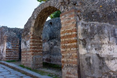 Pompeii, İtalya 'da kaldırımlı bir caddeyi kaplayan antik Roma tuğlaları ve taş kemerler. Antik çağlarda Roma mühendisliğini ve günlük yaşamı gösteren şehir mimarisini korudu..