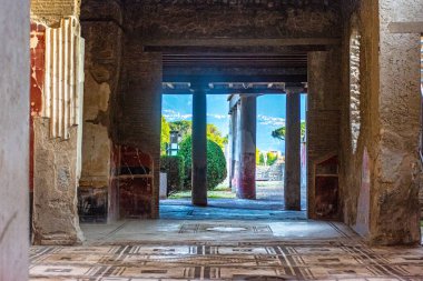 Pompei 'deki antik bir Roma evinin iç manzarasında geometrik mozaik zemin, taş sütunlar ve mimari kalıntılar görülüyor. Harabeler MS 79 'da Vesuvius Dağı' nın patlamasından sonra korundu..