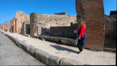 15 Ekim 2019 'da İtalya' nın en ünlü arkeolojik sahalarından biri olan Pompeii antik Roma kalıntıları içinde taş cadde boyunca yürüyen bir turist MS 79 'da Vesuvius Dağı' nın patlamasından sonra korundu..