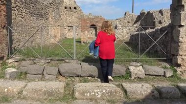 Pompei 'de antik Roma kaldırımına ayak basan bir turist, antik kentin korunmuş kent planlarını gösteren harabeleri ve taş yapıları gözlemliyor..