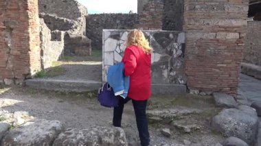 Pompeii 'deki antik bir Roma dükkanına giren turist, antik kentteki ticari yaşamı ve günlük faaliyetleri yansıtan taş bir kapıdan geçiyor..