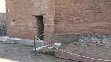 Pompei 'deki antik Roma binasının eğik manzarası, tuğla duvarlar, kapı aralığı ve antik kentteki kentsel yapıyı gösteren muhafaza edilmiş mimari unsurlar içeriyor..
