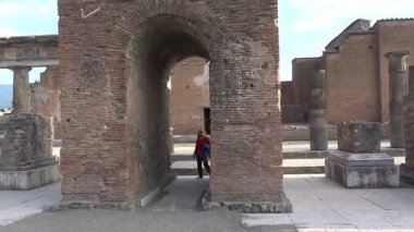 Pompei, İtalya 27 Mart 2025 'te Pompei' de antik Roma kemerinde yürüyen bir turist, tuğla duvarlar ve taş kaldırımlarla çerçevelenmiş, antik kentin korunmuş kentsel yapısını ortaya koyuyor..
