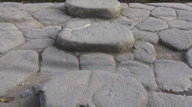 Pompeii 'deki antik bir Roma caddesinde, yayaların su ve molozlardan uzak durarak yolları geçmelerini sağlamak için tasarlanmış taş basamakların yakın görüntüsü..