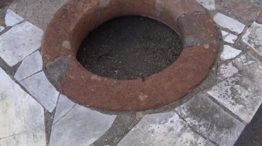 Pompeii 'deki antik Roma atölyesinin yakın plan detayları, yüzeye yerleştirilmiş dairesel taş havzası, Vesuvius Dağı' nın patlamasından önceki ticari mimariyi gösteriyor..