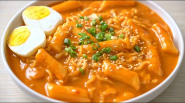 Dilimlenmiş yumurtalarla süslenmiş baharatlı kırmızı sosla servis edilen geleneksel Kore pirinç kekleri. Yerel mutfağı ve Asya mutfağını temsil eden popüler Kore sokak yemekleri.