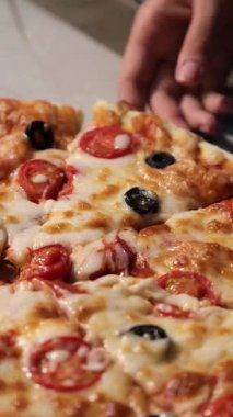 Erimiş peynirli yeni pişmiş pizzanın yakın plan çekimi. Bir el pastadan bir dilim koparırken. Klasik İtalyan konforlu yemekleri, sıradan yemekler ve dayanılmaz ev yemeği konsepti..