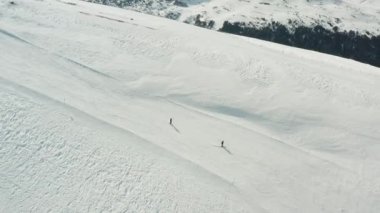Uçsuz bucaksız bir yamaçta ilerleyen iki kayakçının hava görüntüsü. Minimum kış manzarası, açık alan ve güçlü ölçek ve özgürlük hissine sahip açık hava sporları konsepti.