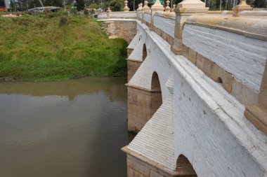 Bogota nehri üzerinde Puente del comn olarak bilinen eski bir koloni taş köprüsü. Arkasında yeşil yüksek ağaçlar ve mavi gökyüzü olan Ulusal Anıt