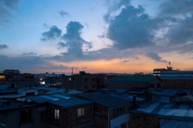 Şehir ışıkları ve anten siluetleriyle sanayi bölgesinde bulutlu gökyüzü ile şaşırtıcı mavi ve turuncu alacakaranlık