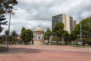 BOGOTA, COLOMBIA -  Gabriel Garcia Marquez Journalist park with simon bolivar temple and office buildings at downtown sunny day clipart