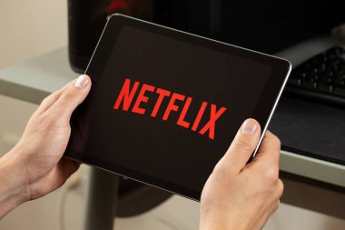 Netflix yayın servisi logosu olan bir tableti tutan bir erkeğe yakın durun.