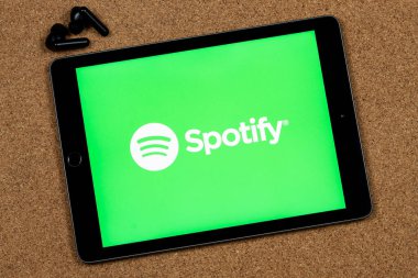 Beyaz renkli iPad 'e yakın siyah kablosuz kulaklıklı dijital müzik logosunu bozuyor.