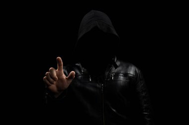 Gölgelerde yüzsüz, kapüşonlu bir adama yaklaş. İşaret parmağı boşluğu işaret ediyor ve siyah bir arka planı var.