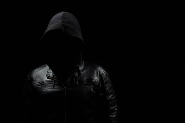 Ekranın solundaki gölgelerde yüzsüz, kapüşonlu bir hacker 'a ve siyah bir arka plana yaklaş.