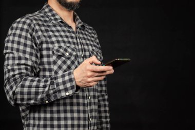 Akıllı telefon tutan bir adama yaklaş. Sağ elini ekranın sol tarafına koy ve siyah arka plan kullan.