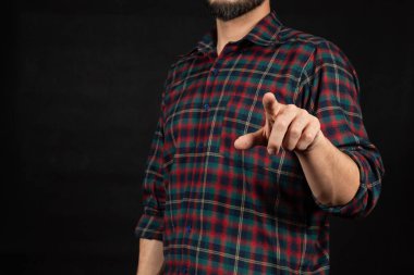 Oduncu gömleği giymiş, sol işaret parmağıyla önündeki boşluğu gösteren bir adama yaklaş.