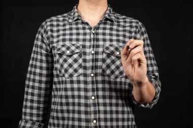 Önündeki boşlukta sol eli ve siyah bir arkaplan ile yazan genç bir adama yakın durun.