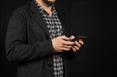 Modern bir delikanlının elinde iki eliyle ekranın solunda akıllı bir telefon tutmasına yakın.