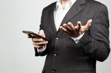 Takım elbiseli bir iş adamının eline kızgın bir jest yapması akıllı bir telefonun ekranını izlemesi.