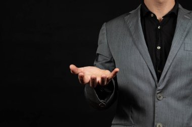 Bir iş adamının sağ eli sağ eli sağ eli ve siyah bir arka planla uzayda bir şey tutmaya hazır.