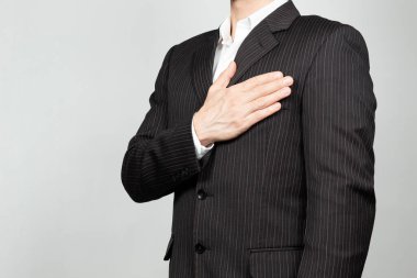 Sağ eli göğsünde ve beyaz bir geçmişi olan takım elbiseli bir iş adamına yakın durun.