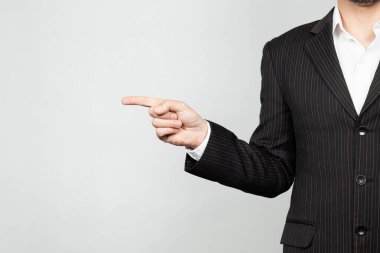 Takım elbiseli bir işadamının sağ işaret parmağı ve beyaz bir geçmişi olan boş bir yeri göstermesine yakın.