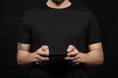 Önünde cep telefonu tutan siyah tişörtlü bir adama yaklaş.