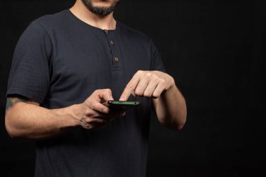 Ekranın sol tarafında mavi tişörtlü bir adama yaklaş ve işaret parmağıyla akıllı telefon ekranını göster.